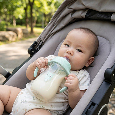Bébé avec biberon menthe dans sa poussette dans le parc