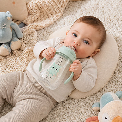 Bébé coucher sur un coussin avec biberon menthe