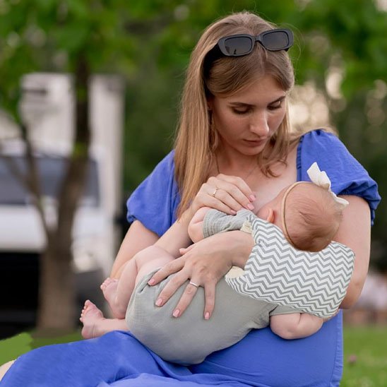 Maman à l'extérieur avec bébé sur brassard d'allaitement