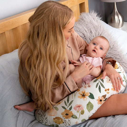 Maman assise avec bébé sur coussin d'allaitement