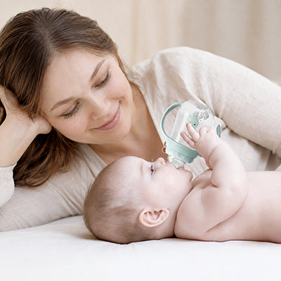 Maman et bébé avec biberon menthe couchés sur un lit