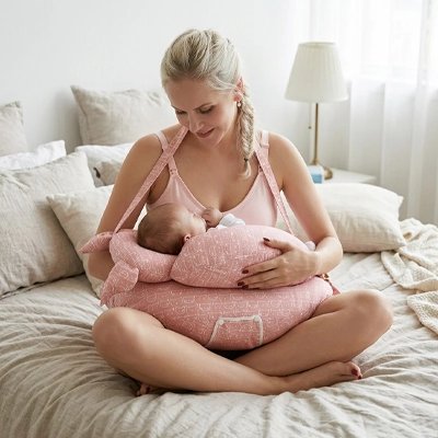 Maman et bébé avec coussin allaitement sur le lit