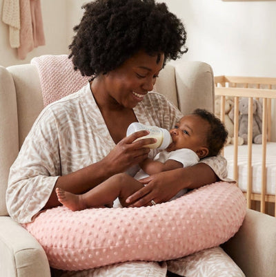Maman donne le biberon à bébé sur coussin pour allaiter