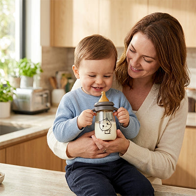 Maman tient bébé avec biberon dans la cuisine